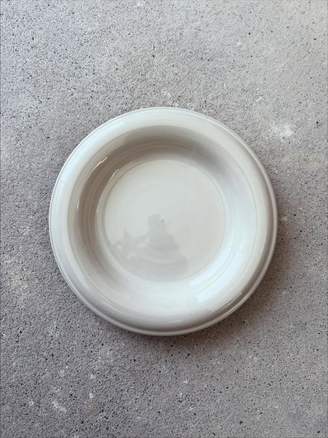 A second white ceramic form photographed on concrete