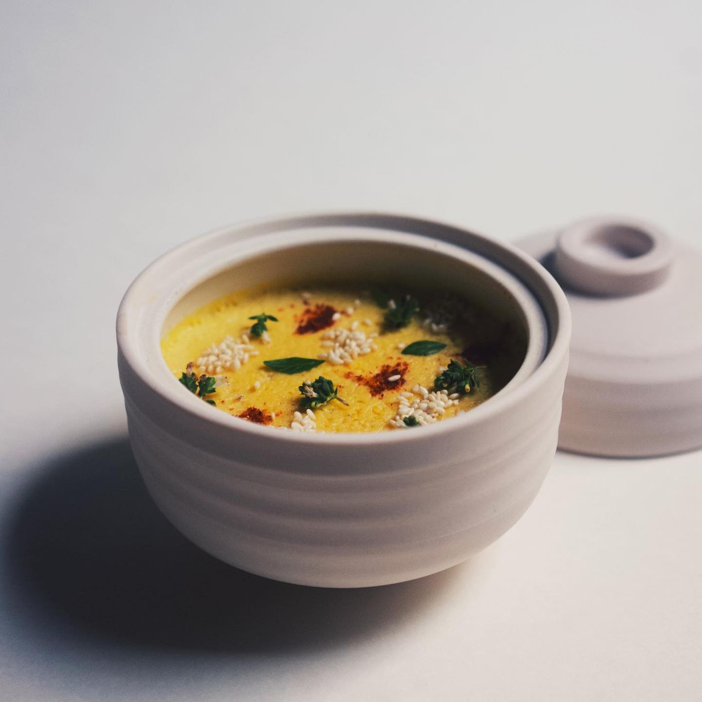 A plated course presented in a white porcelain bowl with its fitted lid