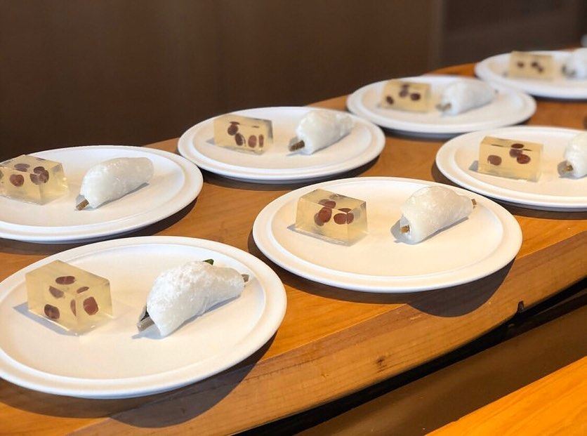 A line of desserts being plated on a wooden restaurant counter