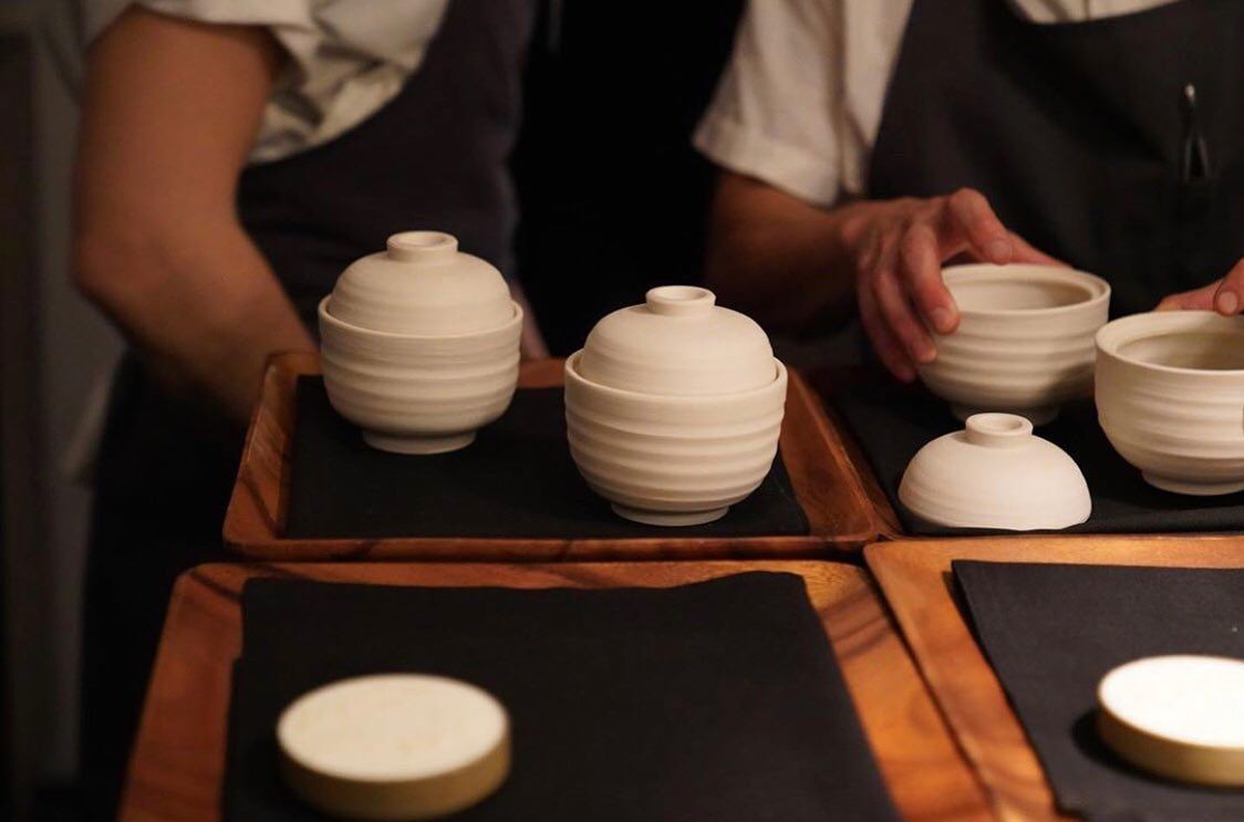 A chef handling a dark textured porcelain gaiwan made for Commis