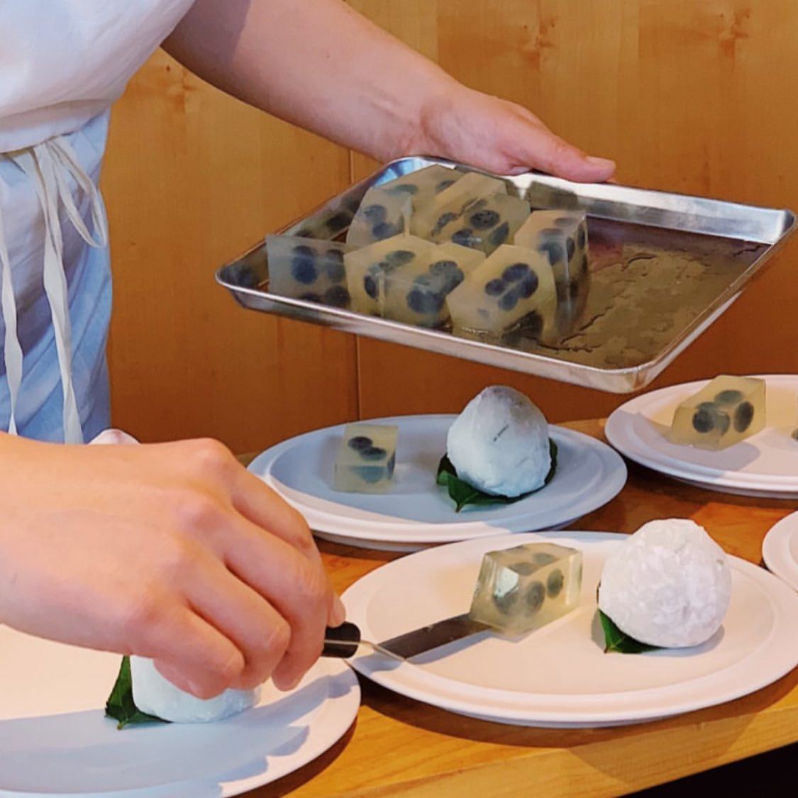 A chef plating several courses on ceramic dishes at Oyatsuya SF