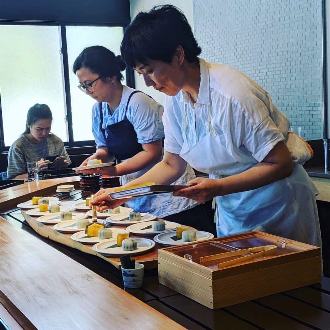 A chef carefully plating a course on ceramic tableware for Oyatsuya SF