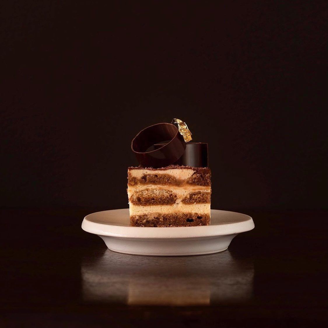 A layered dessert served on a pale ceramic plate against a dark background